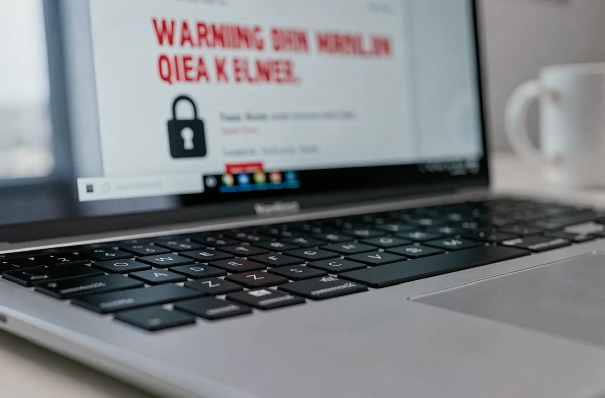 Gros plan sur un clavier d'ordinateur portable avec un avertissement de sécurité des données affiché à l'écran en arrière-plan flou